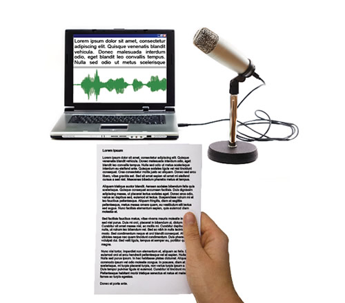 A laptop with Publisher on, a microphone and a hand holding a paper document with text on.
