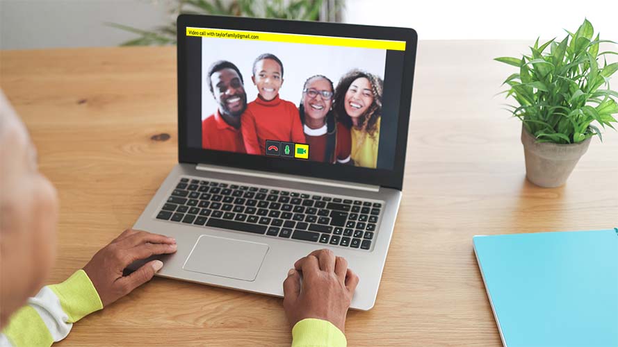 Family waving on a video call shown on a laptop