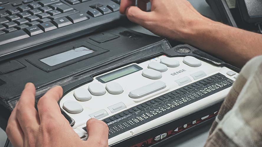 A laptop with Braille input control panel buttons.