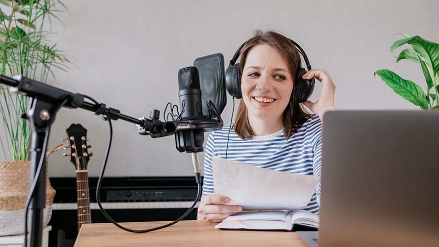 Woman recording a talking book using a microphone and laptop.