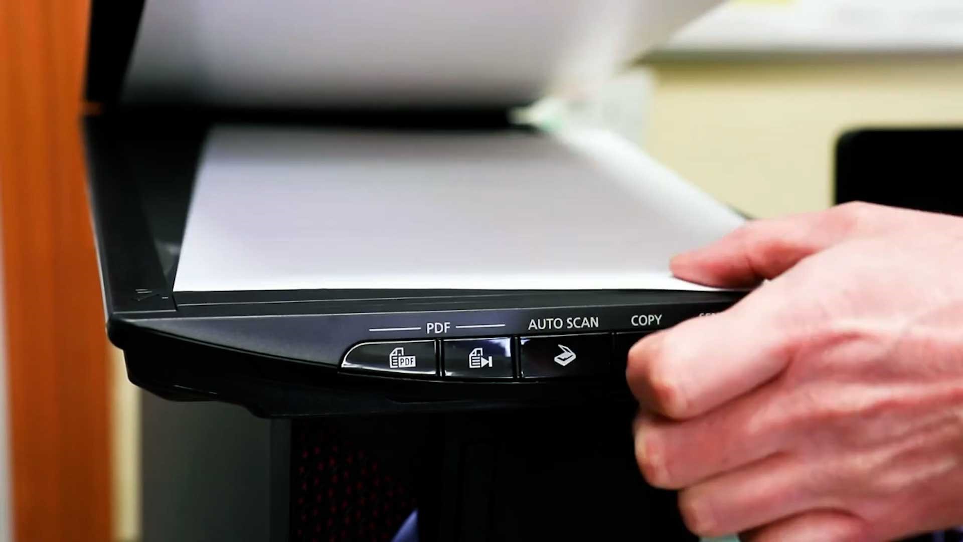 User placing a document into a scanner.