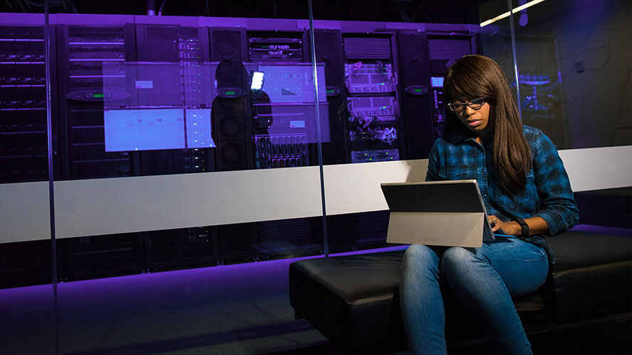 A network manager working on digital tablet in a server room.