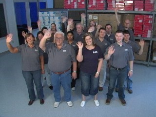 EVAS Team assembled in their warehouse waiving to the camera.